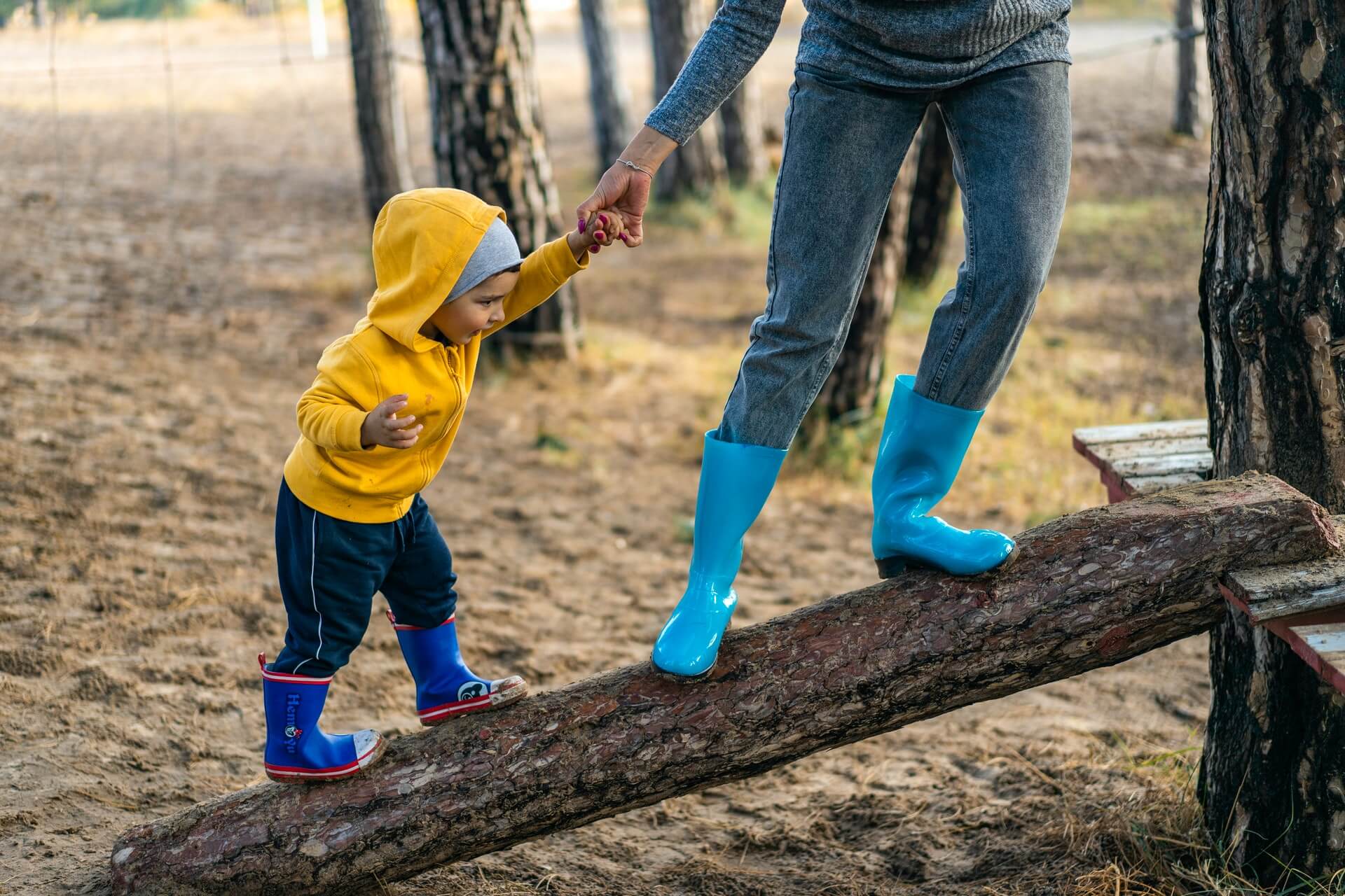 A parent helping child climb a log