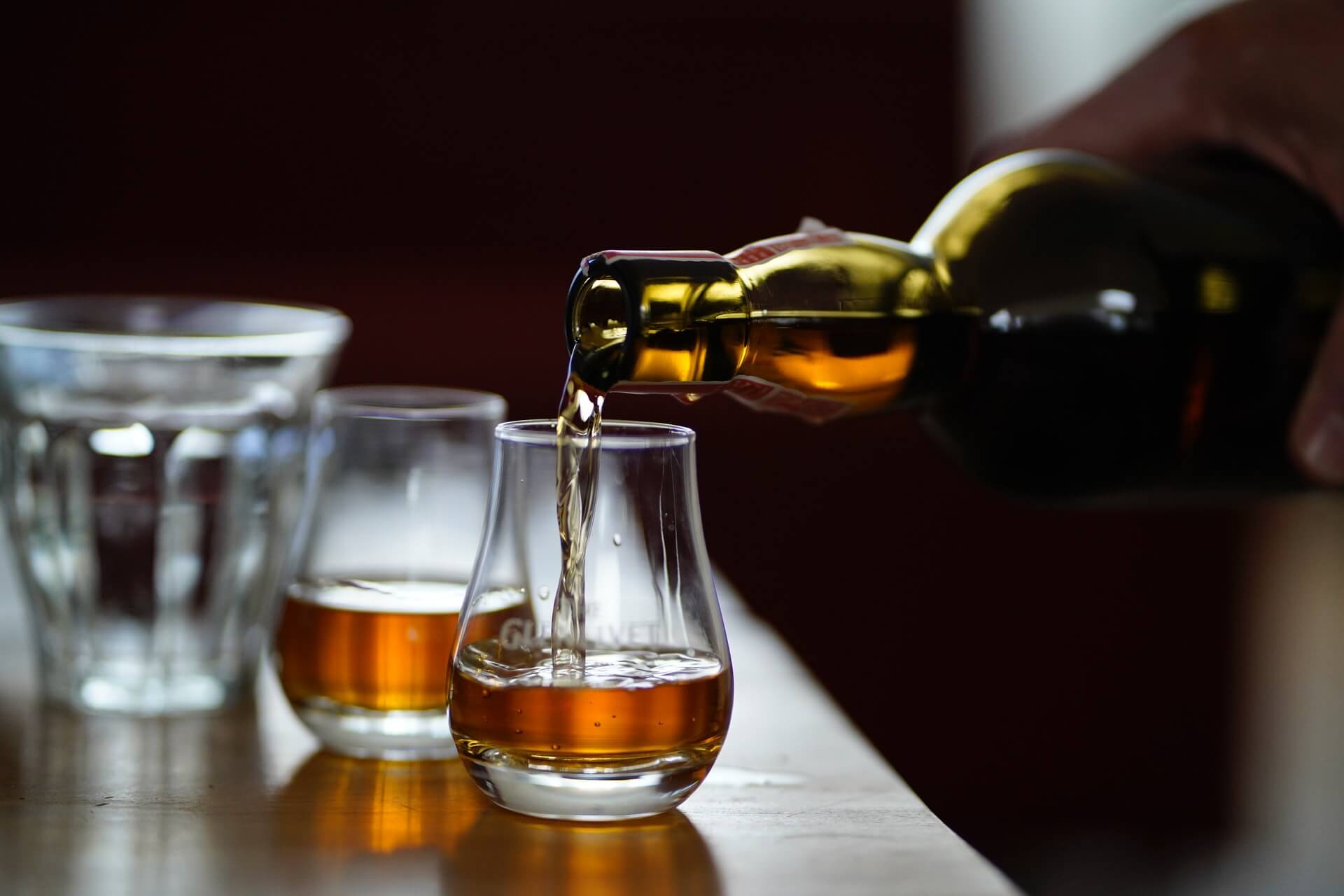 A person pouring whiskey into a glass