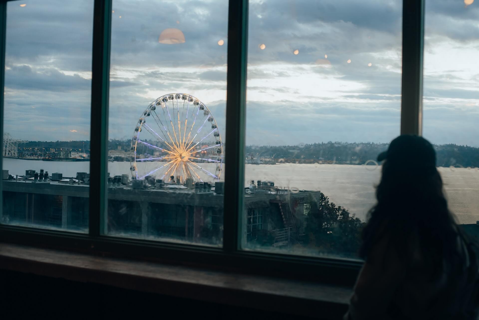 A girl look at a white Ferris wheel near a body of water