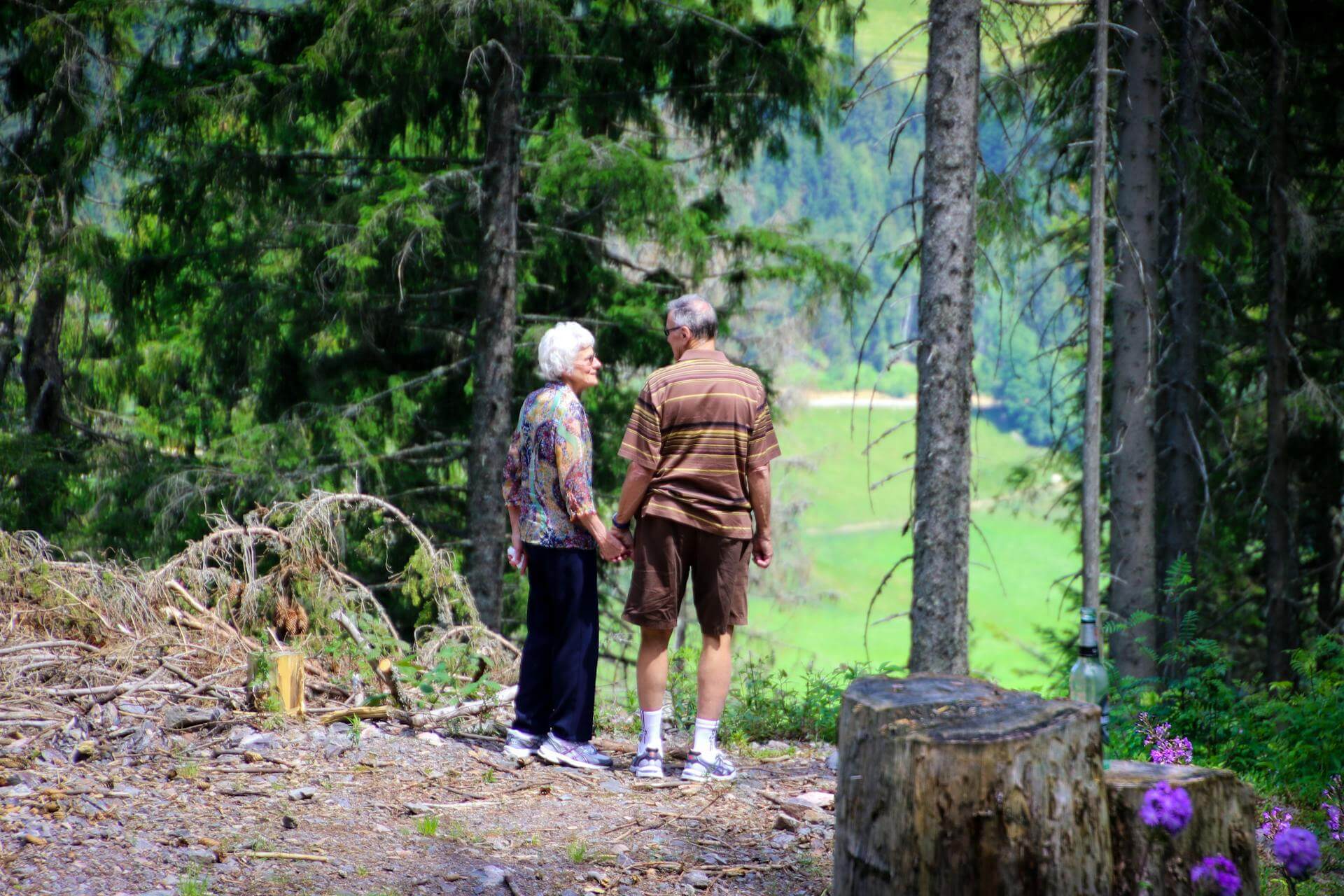 two older people holding hands in a forest