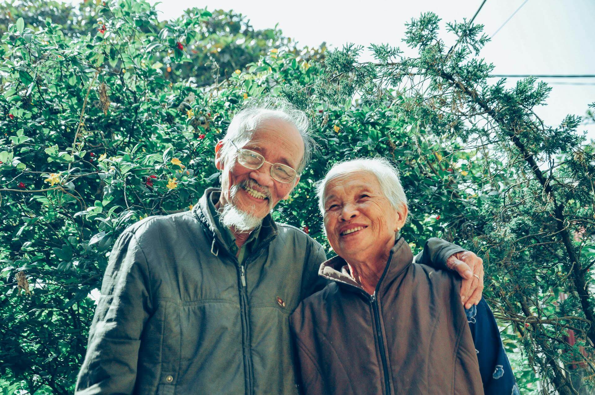two seniors smiling in front of green shrubbery