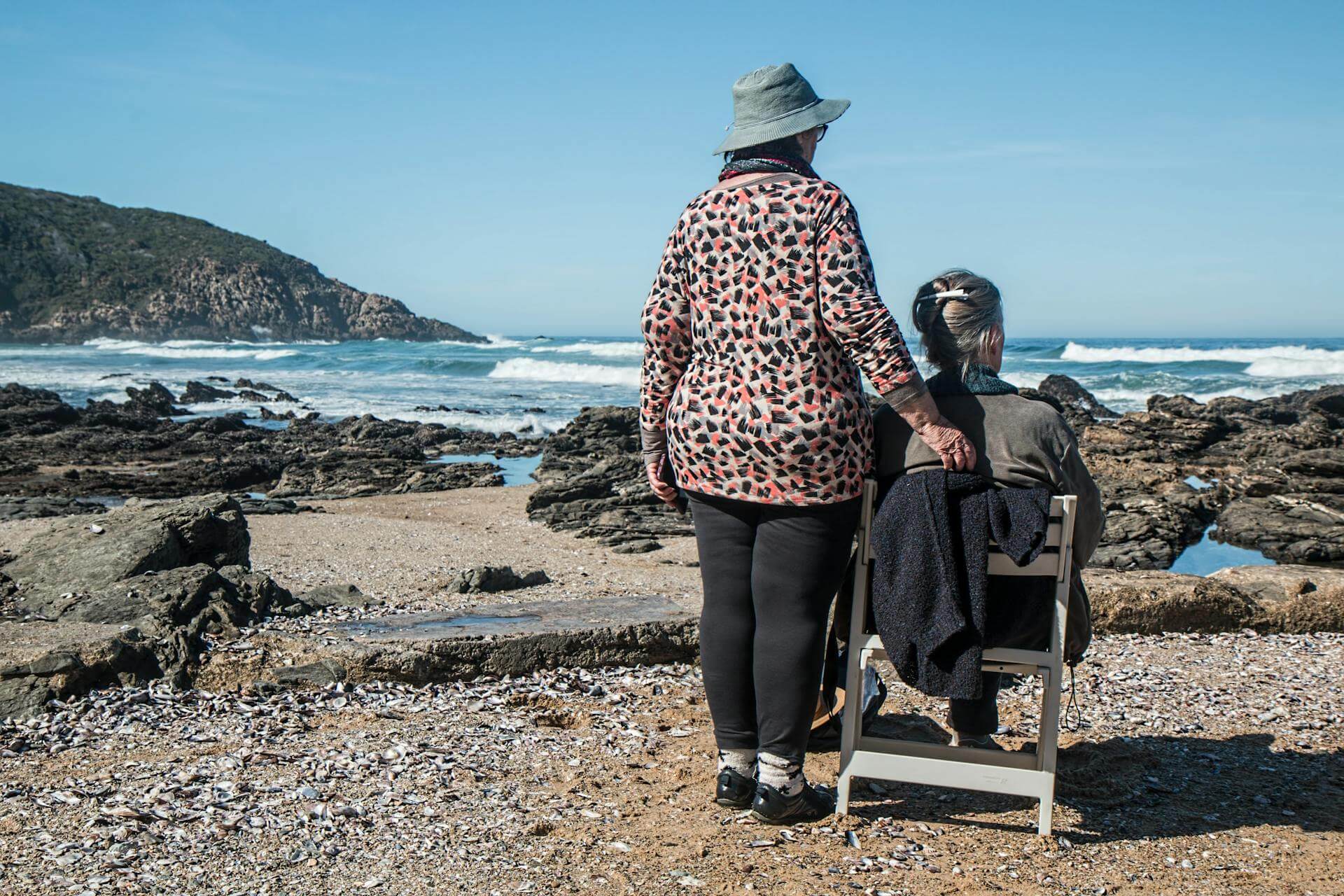two women at the seaside, one sitting on a chair