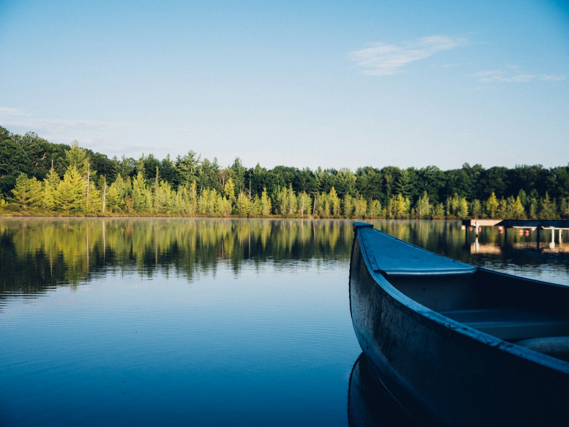Boat bow on a lake with trees and a pier